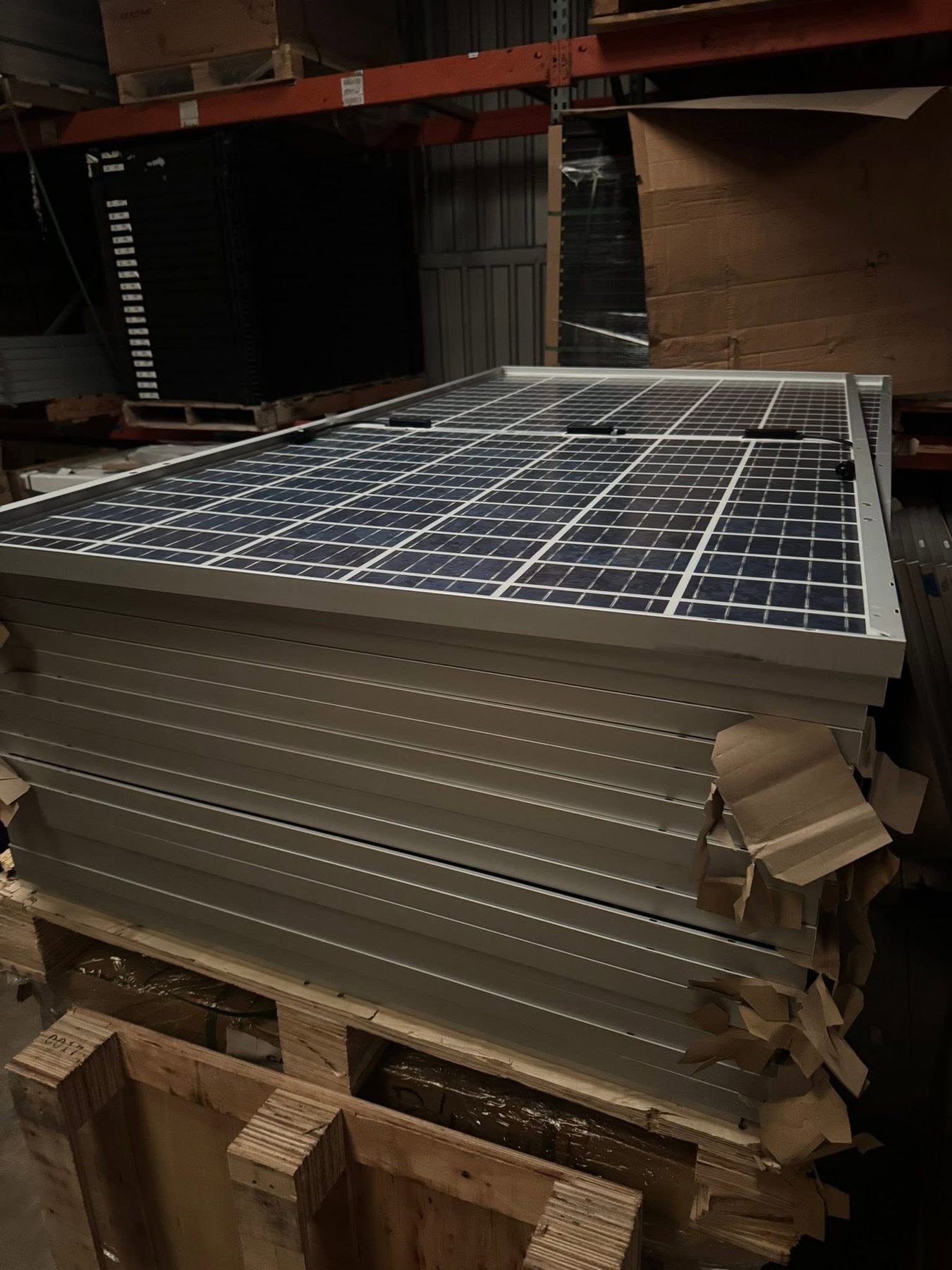 Solar panels stacked on a pallet in a warehouse